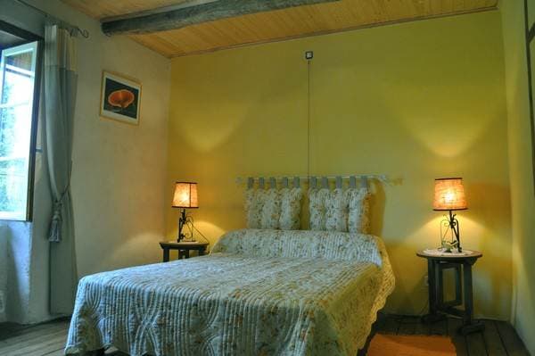 Chambre spacieuse avec murs en pierre apparente et literie confortable.